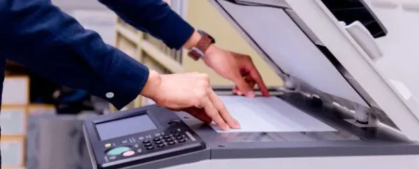 Hand legt ein Blatt auf einen Kopierer
